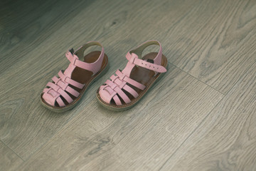Pink baby girl sandals on a hardwood floor