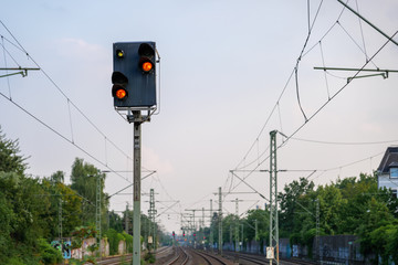 Red traffic light on post over railway train track.  