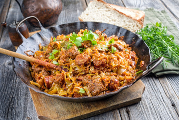 Traditional Polish kraut stew bigos with sausage, meat and mushrooms as closeup in a wrought-iron...