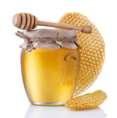 Glass jar full of honey and wooden stick on a white background.