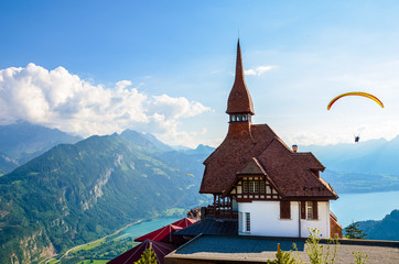 Stunning view of the top of Harder Kulm in Interlaken, Switzerland photographed in summer with paragliders flying around. Hilly Alpine landscape and Lake Thun in background. Paragliding, sunset - obrazy, fototapety, plakaty