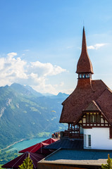 Beautiful top of Harder Kulm in Swiss Interlaken photographed in summer sunset with paragliders flying around. Turquoise Lake Thun in background. Alpine landscape. Travel destination