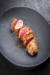 Fried Iberian pork fillet sliced with spice as closeup in a cast iron design plate