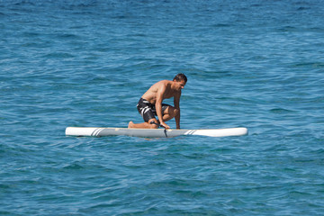 Man gets on the paddle board.