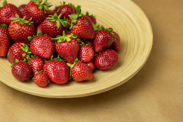 Fresh strawberries in a bowl on wooden table close-up. Healthy food concept, plants, soil, organic natural products, natural food, vegetarian, vegetables, raw, food festival