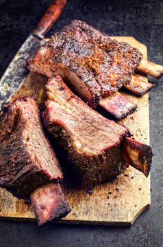Barbecue sliced chuck beef ribs with hot rub as closeup on a wooden cutting board