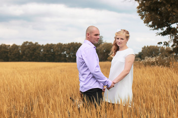 Just married lovers walking in a field in autumn day