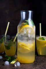 Homemade orange lemonade with citrus and mint on a dark wooden background