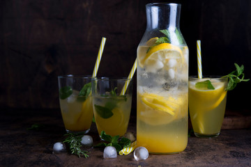 Homemade orange lemonade with citrus and mint on a dark wooden background