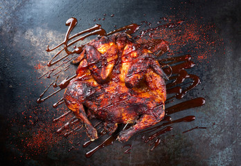Barbecue spatchcocked barbecue chicken al mattone with hot chili sauce as top view on an old metal...