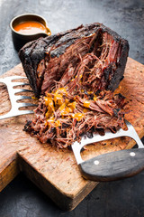 Traditional barbecue wagyu pulled beef with spicy sauce as closeup on a rustic cutting board