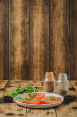 sliced tomatoes and arugula spices salad. In a white bowl on a wooden background. Selective focus