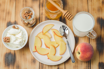 Healthy breakfast background. Peach, honey, milk, cottage cheese and walnut on a wooden background. Top view