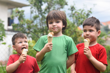 Three happy little boy eating ice cream. Closeup of children eating ice cream in the park