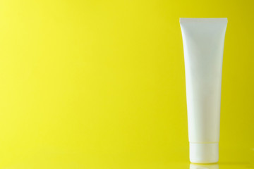 White tube with cream on a yellow background, side view, a place for an inscription