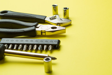 Metal tools on a yellow background, screwdriver and pliers