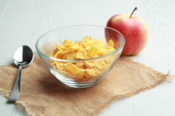 Cornflakes glass bowl, metal spoon, apple