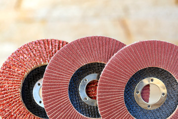 Flap grinding wheels of different grains on wood and metal on a light beige background in unsharp.