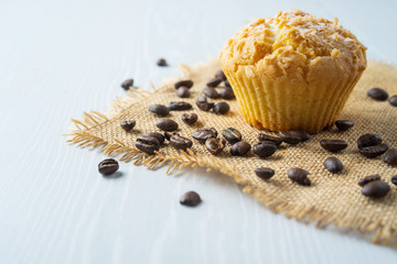 Baked cupcake on white table, coffee grains, side view