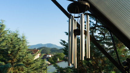 Garden decoration, wind chimes hanging under the roof of the balcony of a house. Cypress tree in the street of a neighborhood in a small town.