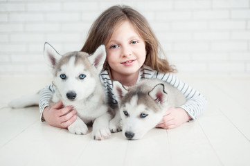Cute little girl hugging husky puppy on a white background.