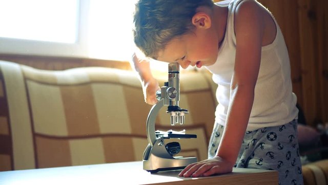 Boy adjust microscope on table