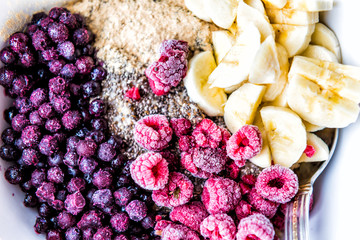 Frozen blueberries, raspberries, banana, maca and chia seeds toppings on oat porridge