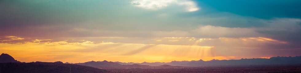 Panorama of colorful clouds at sunset over an urban environment with mountains in the distance