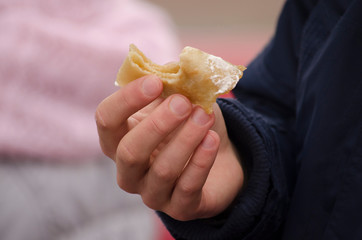 Man's hand holds a bitten pancake. Street food.