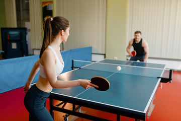 Man and woman playing ping pong indoors