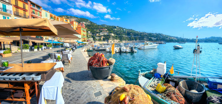 Street scene with cafe and fishing boat in resort town Villefranche-sur-Mer. Cote d'Azur, France