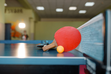 Two ping pong rackets and ball on table with net