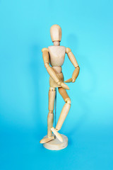 yellow wooden maniken is dancing and doing poses on blue background