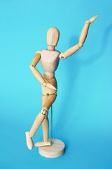 yellow wooden maniken is dancing and doing poses on blue background