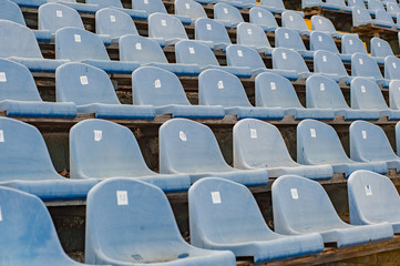 Naklejka premium Sports concept. Rows of empty grey blue plastic seats at the tribune in an open sports stadium