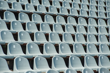 Sports concept. Rows of empty grey blue plastic seats at the tribune in an open sports stadium