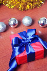 red gift box with blue bow on the background of Christmas toys for the new year holiday