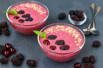 Healthy breakfast smoothie bowl with blackberries, cherries and oatmeal on dark background, horizontal photo