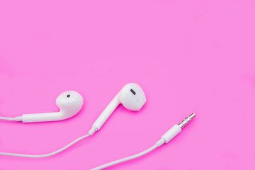 White earphones on pink background with copy space and clipping path. Flat lay. Top view.