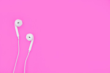 White earphones on pink background with copy space and clipping path. Flat lay. Top view.
