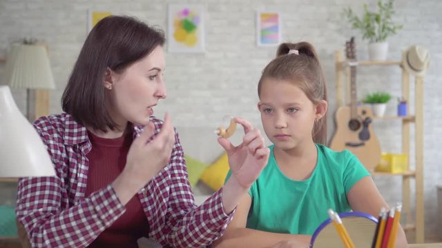 young woman tells a teenage girl about a hearing aid