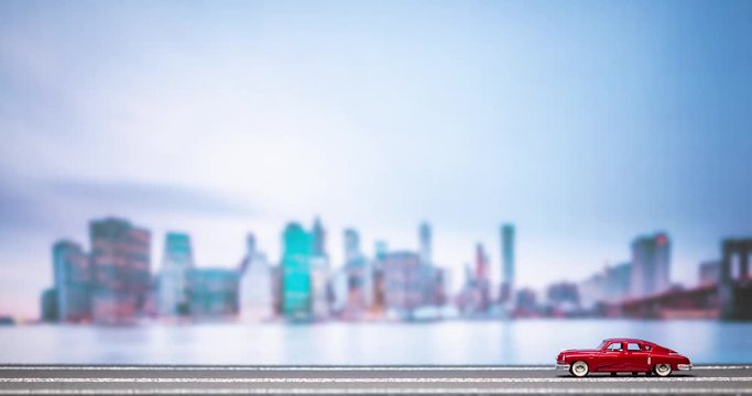 Time lapse of a red retro car figurine moving from right to left on a highroad model with a city image in the background, passing twice.