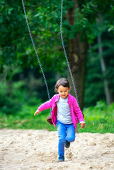 Cute little girl playing on swing in park