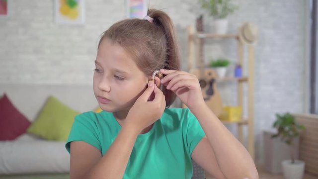 Portrait hard of hearing teen girl with hearing aid in ear