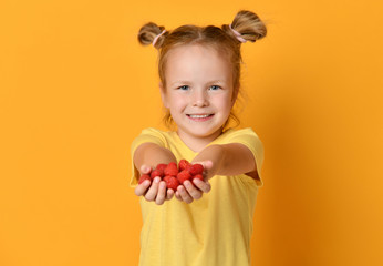 Young girl kid in blank t-shirt  hold raspberries fruits in hands happy on yellow 