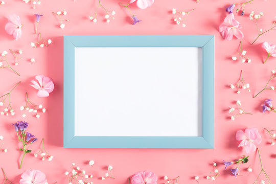 Beautiful flowers composition. Empty photo frame, pink flowers on pastel pink background. Valentines Day, Easter, Birthday, Happy Women's Day, Mother's day. Flat lay, top view, copy space