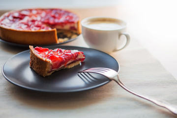 Still life with a Cup of coffee and sweet dessert with strawberries, cheesecake cake with slices of berries in jelly on top.