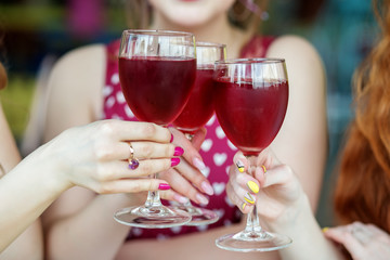 Glasses of red wine in female hands. Toast at a party. The concept of alcohol, holiday