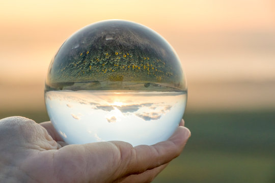 Crystal ball photography - sunset nature landscape, hand holding the ball