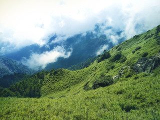 Clouds on a high mountains with green fields